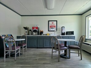 A small, clean cafe with a coffee machine, a microwave, and a few chairs.