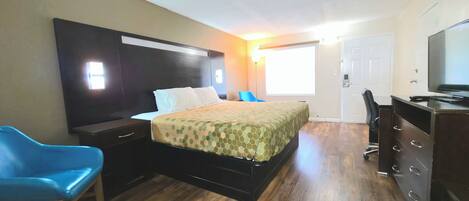 A hotel room with a bed, a desk, a chair, and a television.