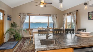 A kitchen with a large island, a ceiling fan, and a view of the sea. - Lakeshore Vermont (Colchester)