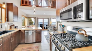 A modern kitchen with stainless steel appliances, wooden cabinets, and a large island. - Lakeshore Vermont (Colchester)
