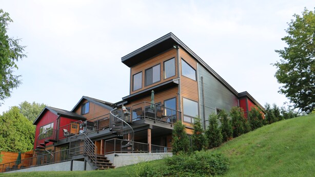 A modern multi-story building with a prominent staircase, large windows, and a red exterior. - Lakeshore Vermont (Colchester)