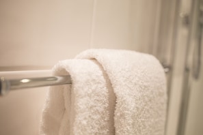 A white towel hanging on a metal towel rack in a bathroom. - Plummer House (Newcastle-upon-Tyne)
