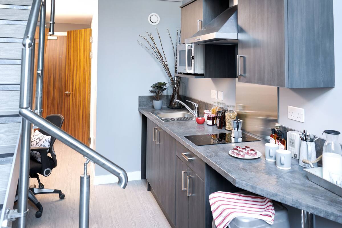 A modern kitchen with a built-in microwave, stainless steel sink, and wooden cabinets.