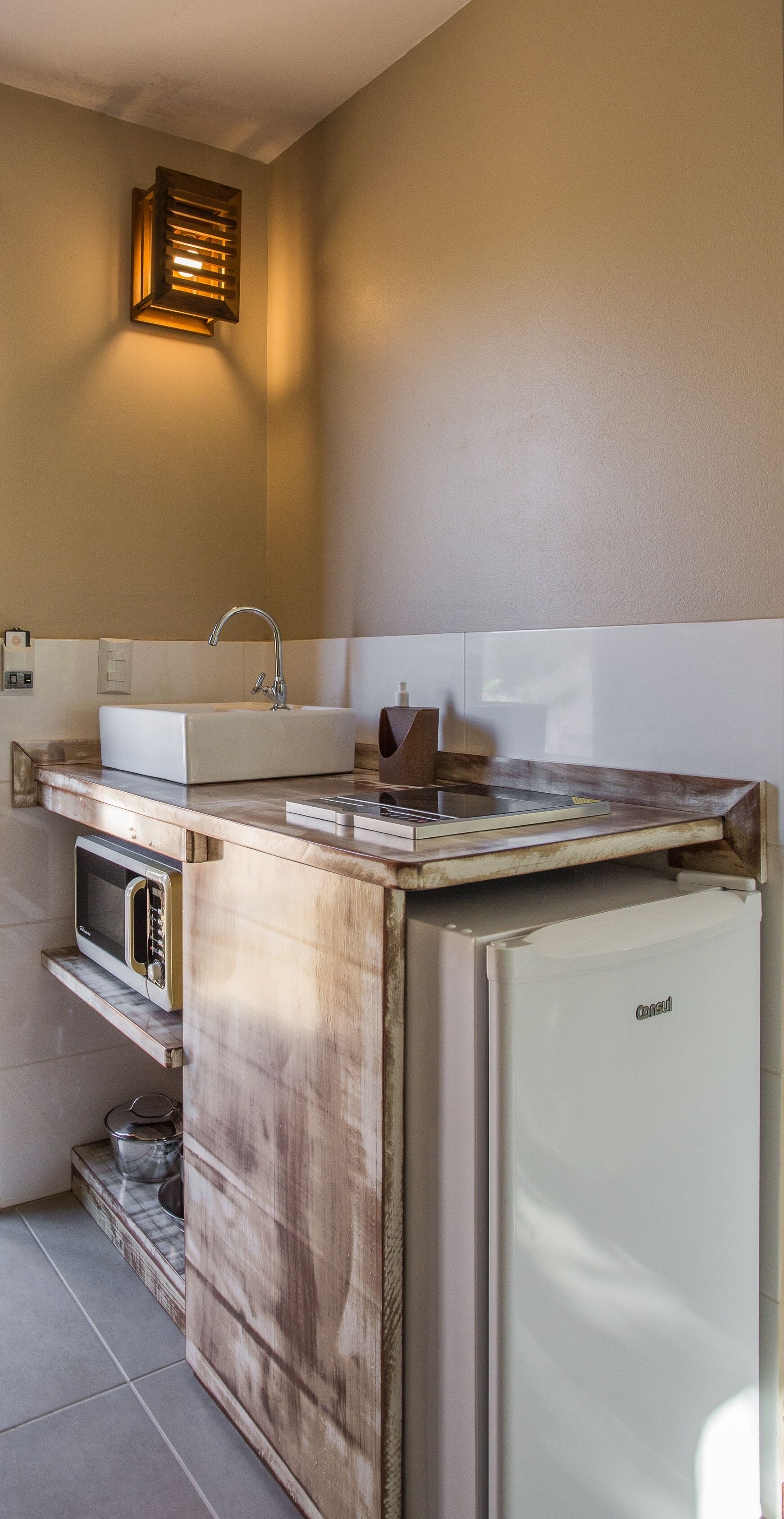 Una cocina compacta con microondas integrado, un lavabo y un refrigerador.