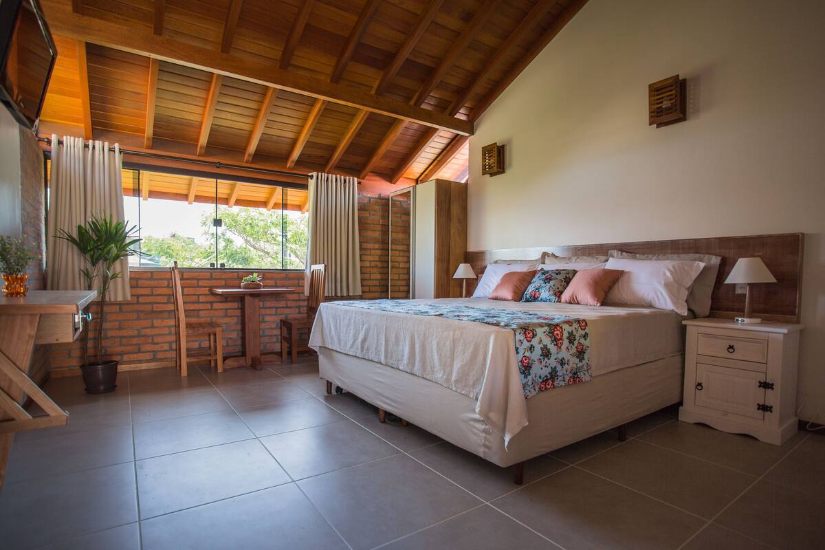 Un dormitorio con una cama grande, un escritorio y una ventana con cortinas.