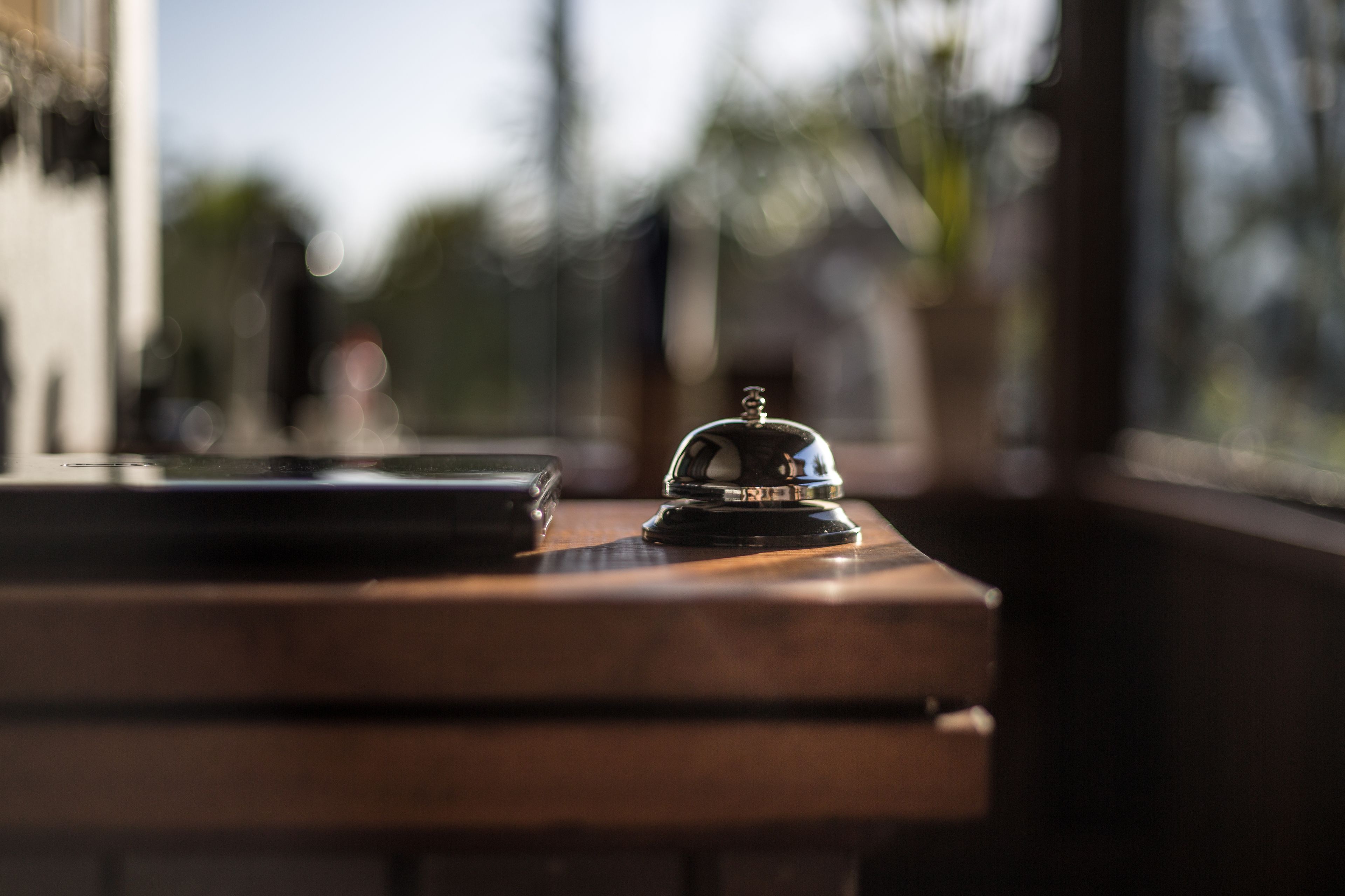 A wooden table with a bell and a smartphone.