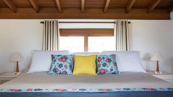 A bedroom with a bed, two nightstands, a window with curtains, and a wooden ceiling.