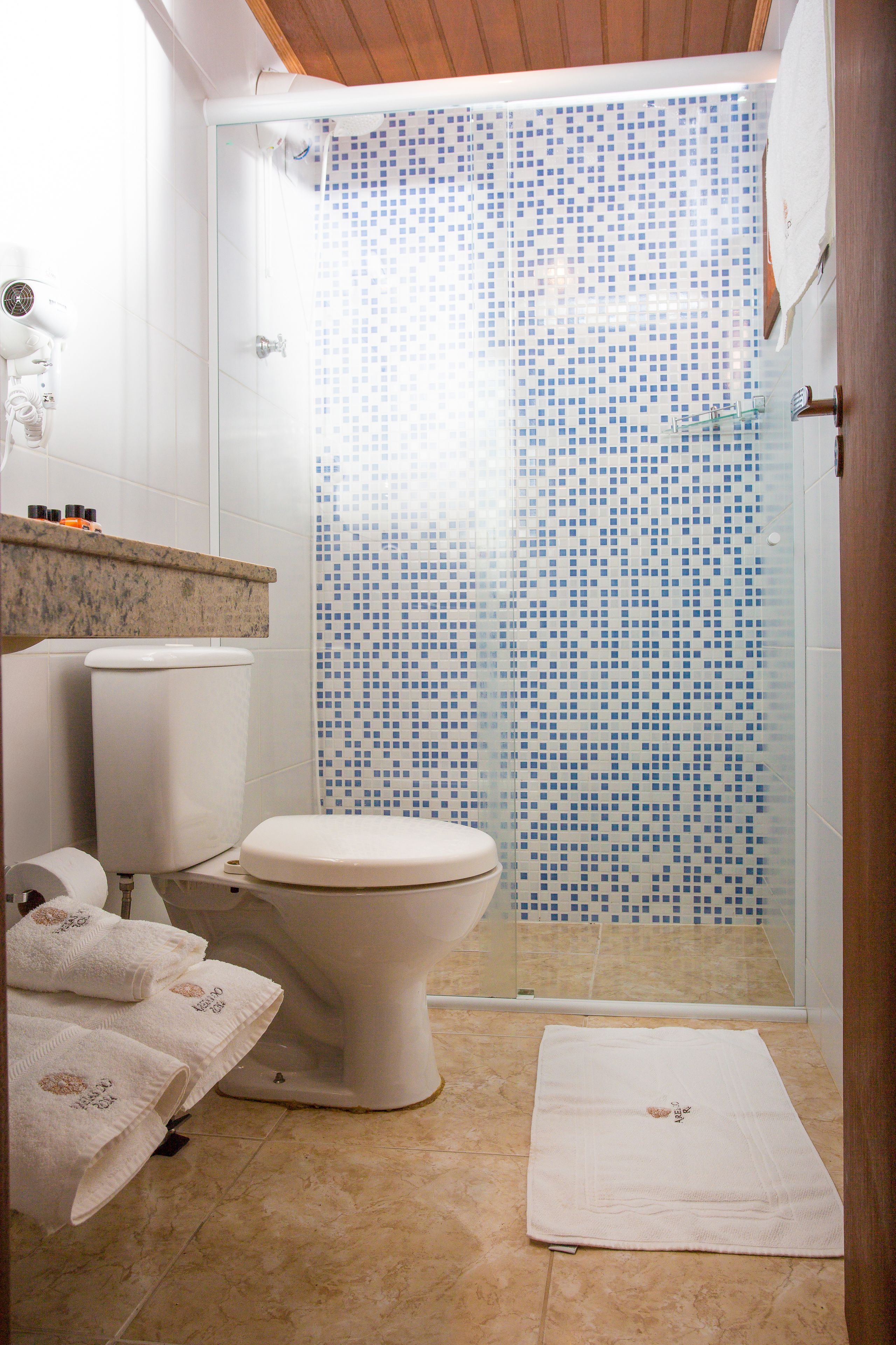 Un baño con ducha, inodoro y toallero.