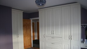 A room with a large white wardrobe, a wooden door, and a grey carpet.