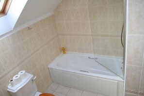 A bathroom with a bathtub, toilet, and a shower area.