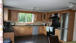 A kitchen with wooden cabinets, a stainless steel refrigerator, and a window providing natural light.