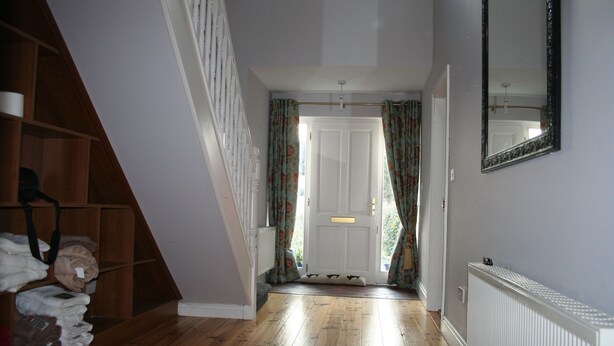 A hallway with wooden flooring, a white radiator, and a door with curtains.