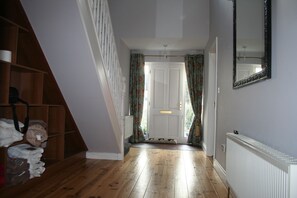 A hallway with wooden flooring, a white radiator, and a door with curtains. - Lios Mór - 5 bed self catering house (Westport)