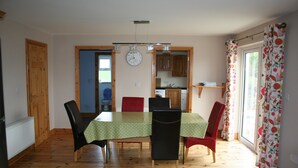 A dining area with a table set for six, surrounded by chairs. A clock is mounted on the wall above the table.