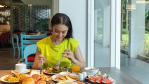 Un coin repas avec une table mise pour le petit-déjeuner, comprenant divers plats et un verre de jus d’orange.