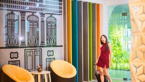 Un intérieur moderne agrémenté d’une fresque représentant une architecture traditionnelle, d’un coin salon avec deux fauteuils et d’un panneau vertical aux couleurs vives.
