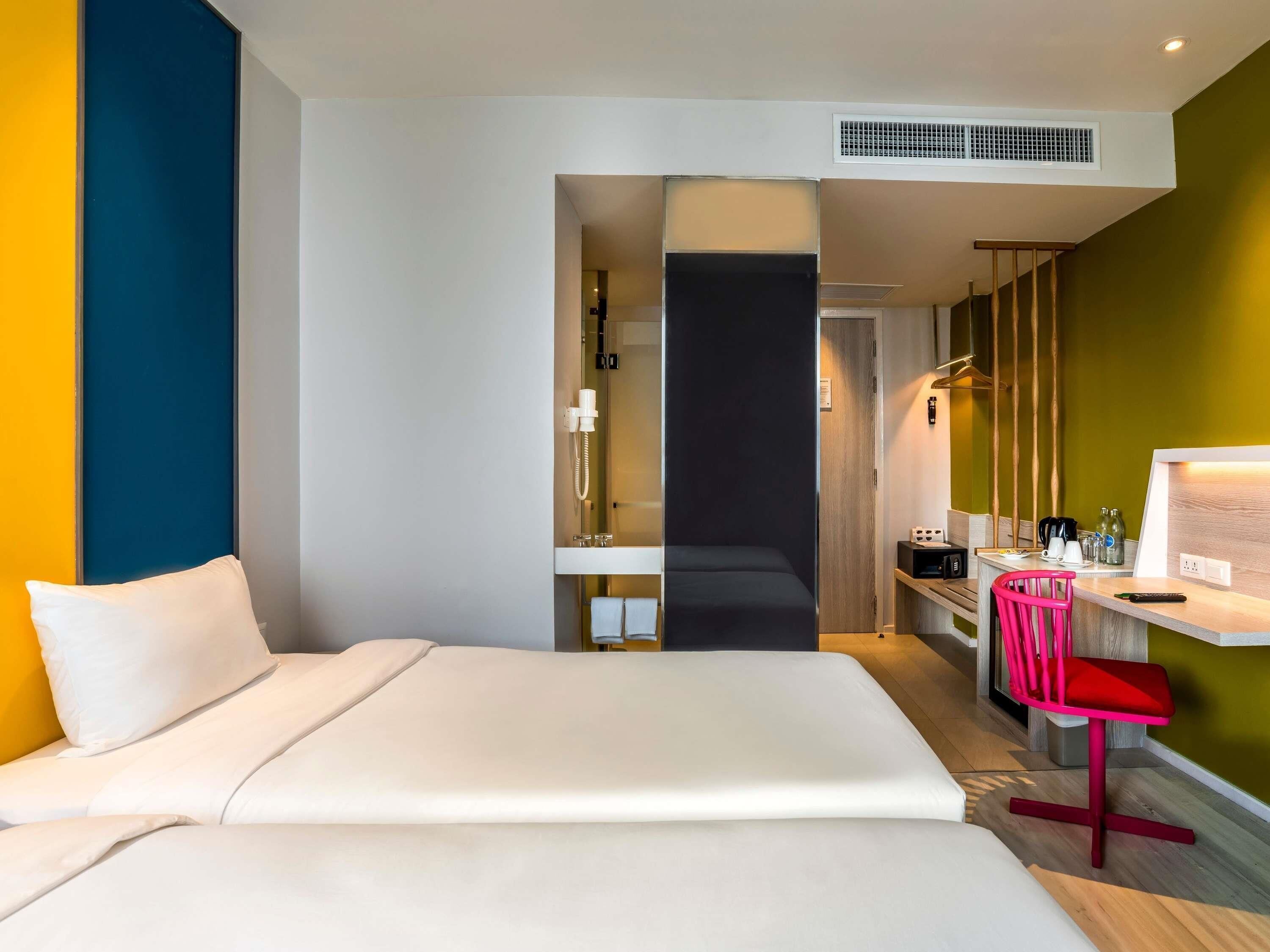 Habitación de hotel con cama, escritorio, silla y kitchenette.