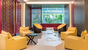 Un espace détente moderne avec des canapés jaunes, un canapé rouge et une table basse en verre.