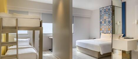 Habitación de hotel con literas, una cama individual, baño con espejo y ventana.
