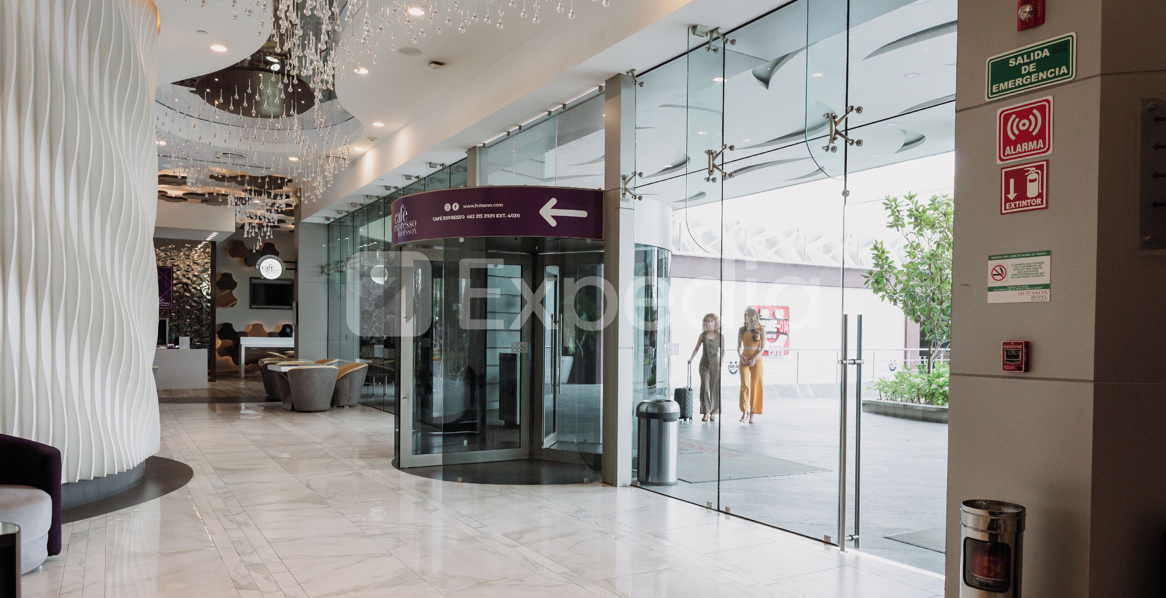 Een hotel lobby met glazen entree, een routebord en tekens voor nooduitgangen.