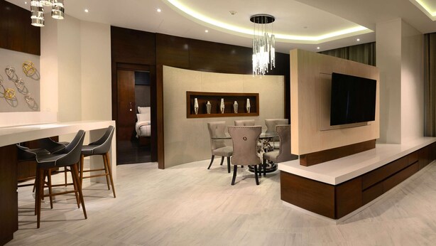 A modern living room with a TV, a sofa, a dining area, and a bar. - HS HOTSSON Hotel Irapuato (Irapuato)