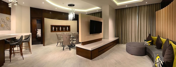 Uma sala de estar moderna com televisão, sofá, área de jantar e bar.