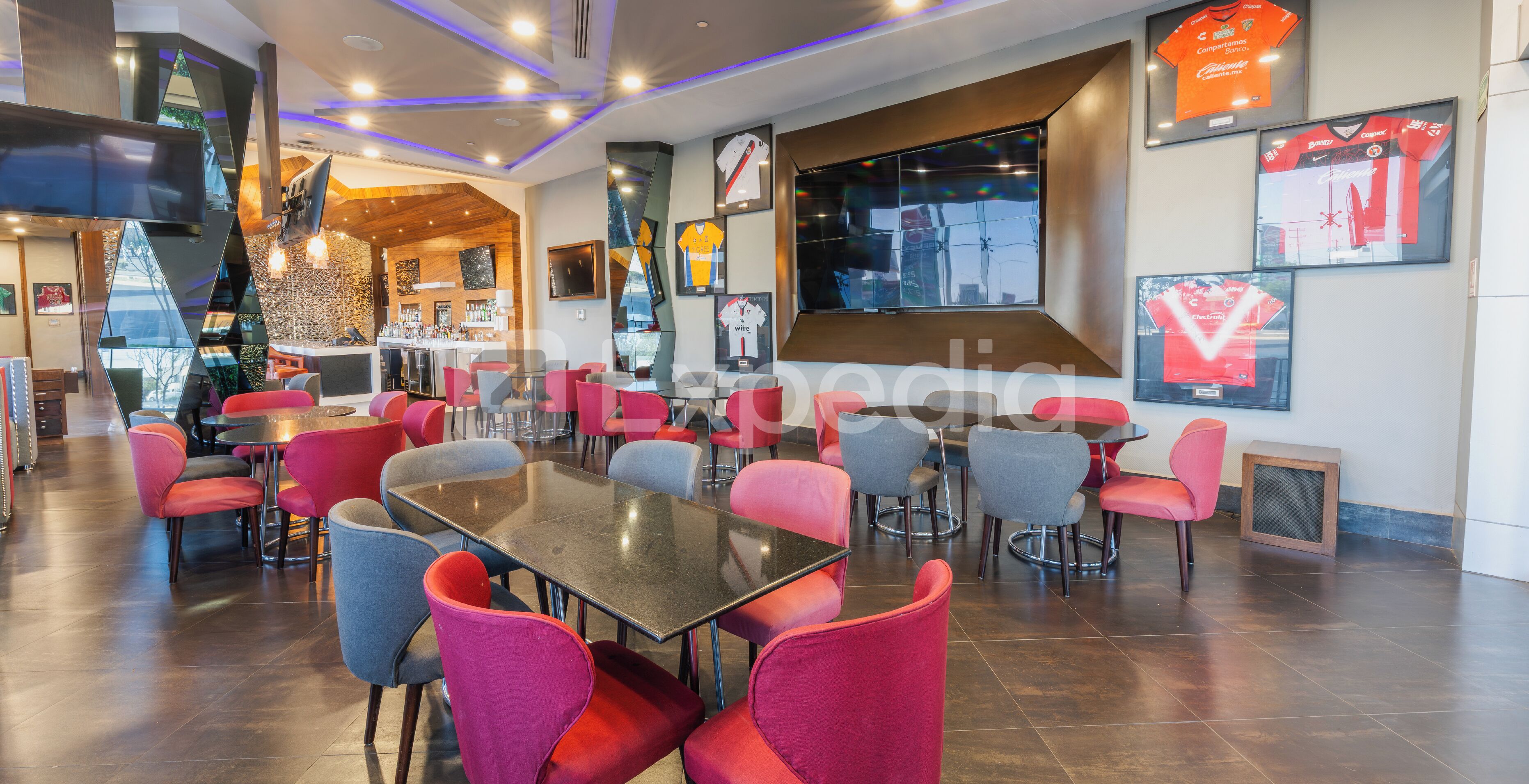 Ein modernes Restaurant mit mehreren Tischen und Stühlen, einer Bar und Sporttrikots an den Wänden.