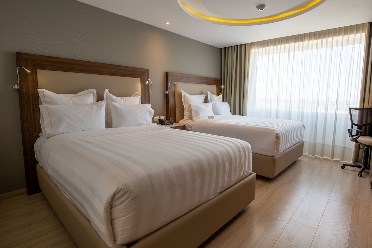 Ein Hotelzimmer mit zwei Betten, einem Schreibtisch und einem Sessel.
