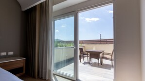 A hotel room with a bed, a desk, and a balcony with a table and chairs. - HS HOTSSON Hotel Irapuato (Irapuato)