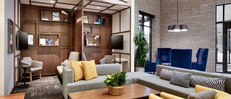 A modern interior with a sectional sofa, armchairs, a coffee table, and a TV.