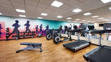 A gym with treadmills, elliptical machines, and a bench.