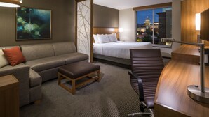 A hotel room with a bed, a sofa, a desk, and a view of a cityscape. - Hyatt Place Boise/Downtown (Boise)