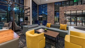 A modern lobby with a seating area, large windows, and a brick accent wall. - Hyatt Place Boise/Downtown (Boise)