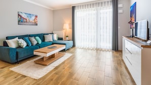 Uma sala de estar moderna com um sofá verde-turquesa, uma mesa de centro de madeira e uma janela grande com cortinas leves.