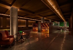 Een ruime lobby met een modern design, met een lederen fauteuil, een ronde tafel met een kaars, en een decoratieve wand met een geometrisch patroon.