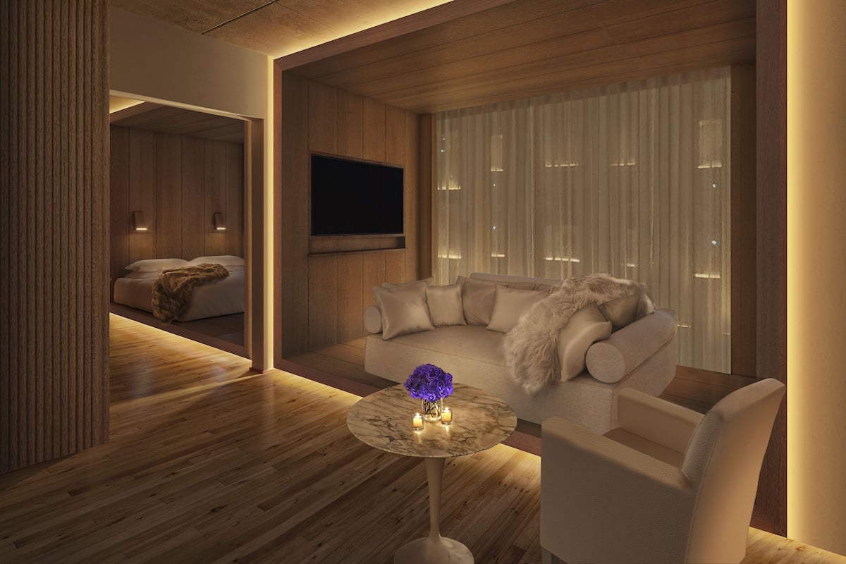 A modern living room with a wooden floor, a round marble coffee table, a beige sofa, and a television mounted on the wall.