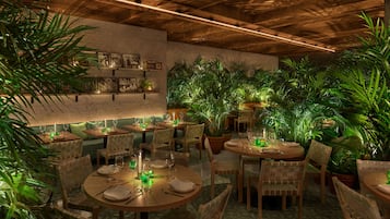 Un restaurante con mesas y sillas de madera, rodeado de exuberante follaje verde.