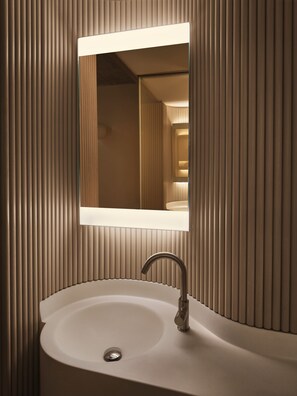 A bathroom with a sink, mirror, and vertical wooden paneling.