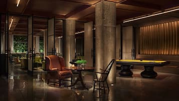 A spacious lobby with a pool table, comfortable seating, and a view of greenery outside.