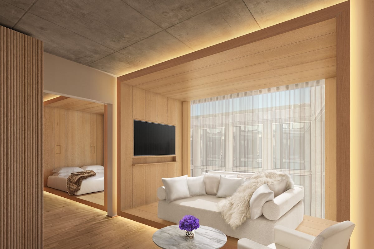 A modern living room with a wooden floor, a white sofa, a round table with a vase, and a large window with sheer curtains.