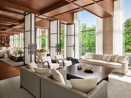 A spacious living area with a large window, a sofa, a coffee table, and a bookshelf.