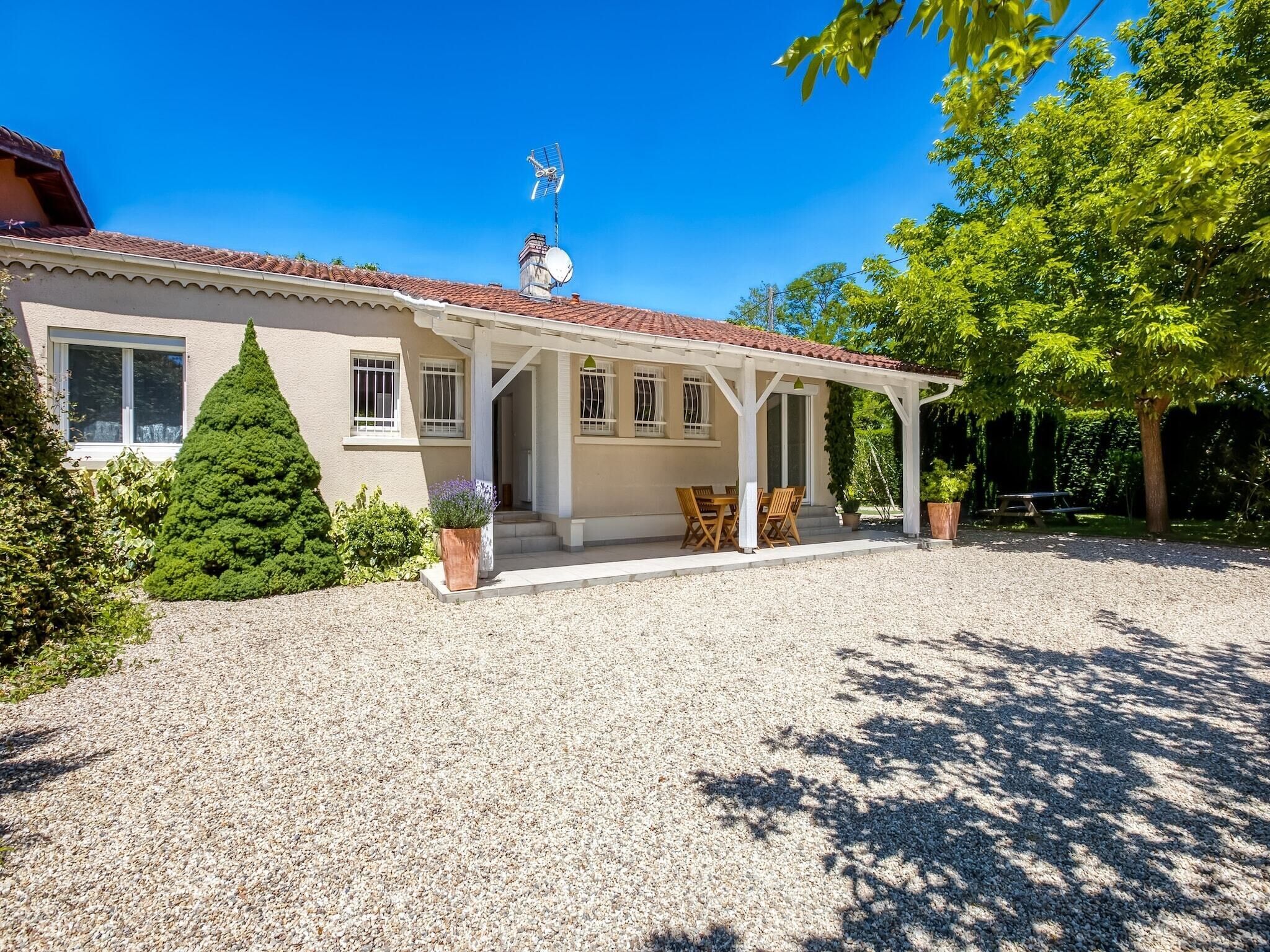 Ein Haus mit überdachter Veranda, Satellitenschüssel und Auffahrt mit Kies.
