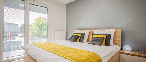 A modern bedroom with a large bed, a view through a sliding glass door, and a skylight.
