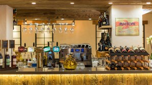 Een bar met verschillende drankkranen, een koffieapparaat en een wijnrek.
