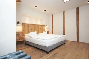 A modern bedroom with a wooden headboard, a large bed, bedside lamps, and a wooden floor. - Hotel Malé Versailles (Karlovy Vary)