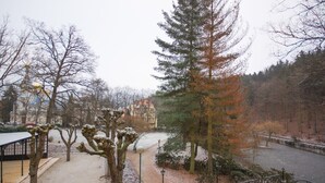Een park met een rivier, bomen en een tuinhuisje.