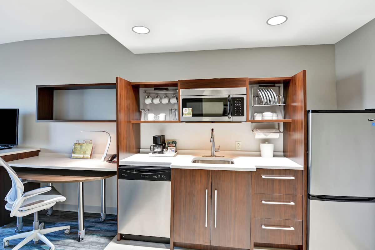 Una cocina compacta con microondas, cafetera y refrigerador.