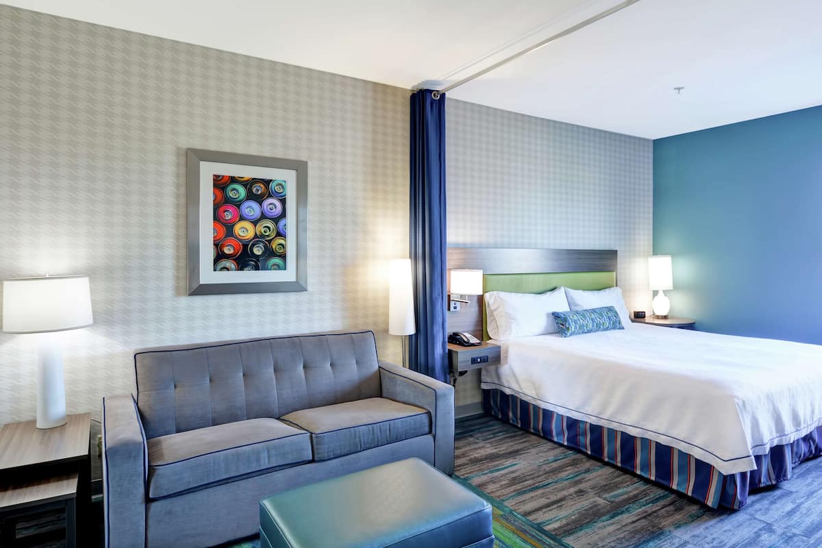 Una habitación de hotel con cama, sofá, escritorio y mesita de noche.