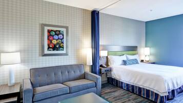 A hotel room with a bed, a sofa, a desk, and a nightstand.