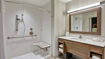 Une salle de bain moderne avec une douche à l’italienne, un meuble-lavabo avec un miroir et un porte-serviettes.
